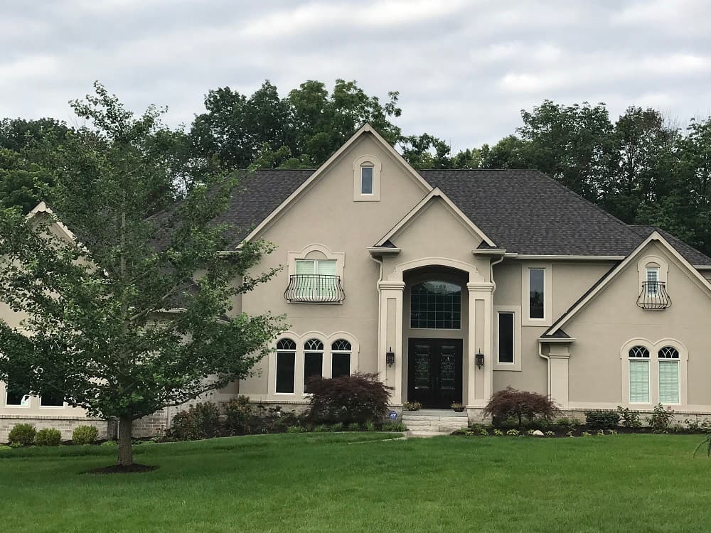 A home with stucco siding and black roofing.